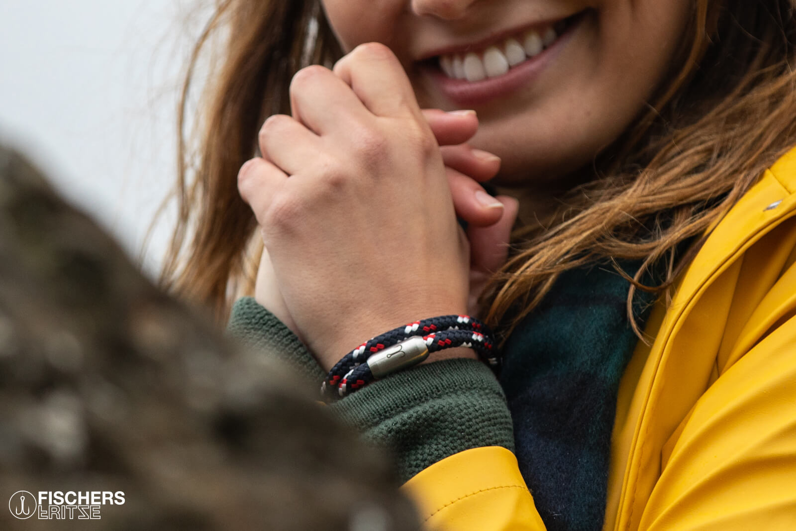 Junge Frau lächelt, traegt ein Segeltau Wickelarmband von Fischers Fritze in marineblau rot weiss